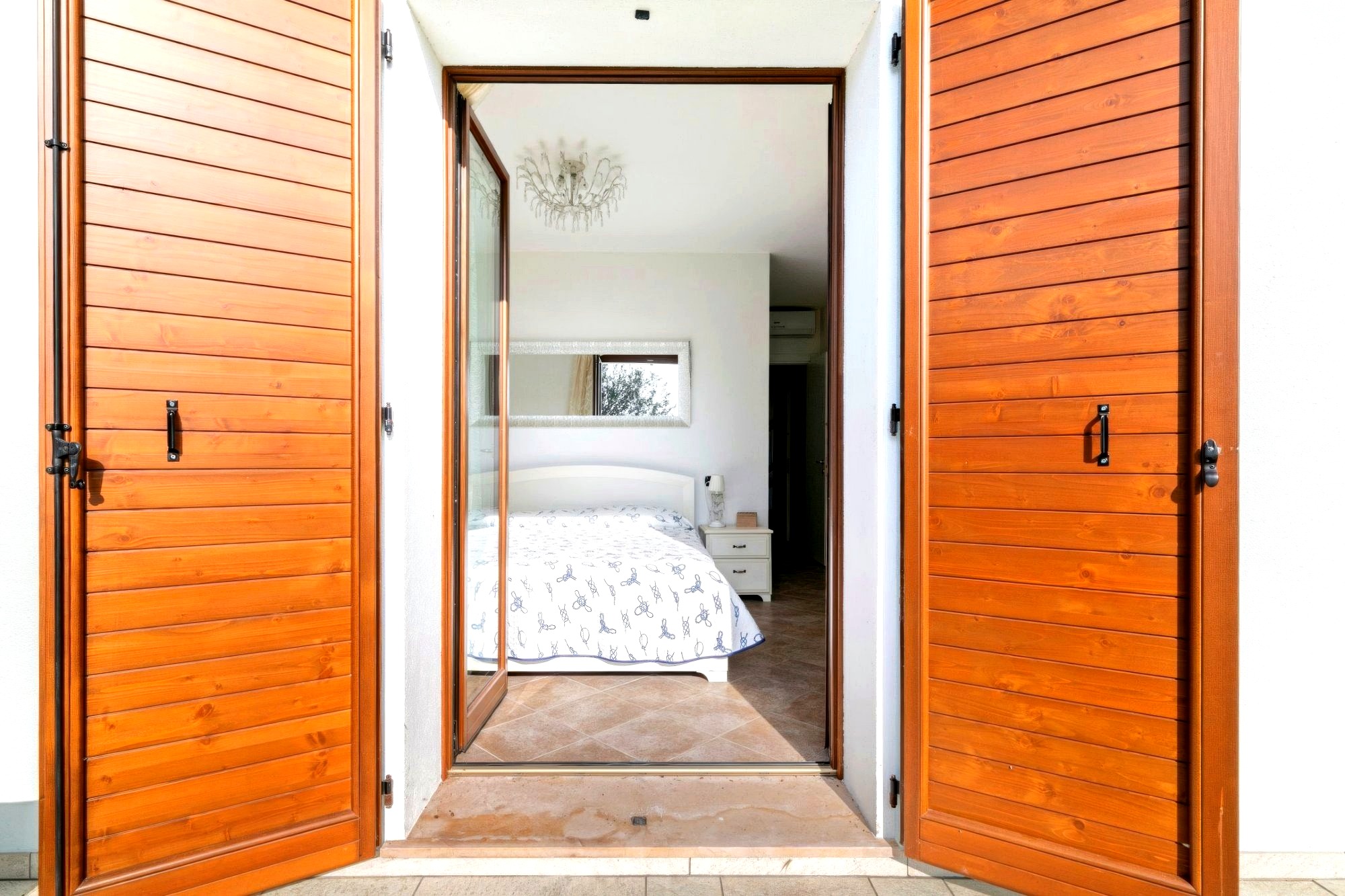 Villa Albarella bedroom with wooden shutters opening to garden